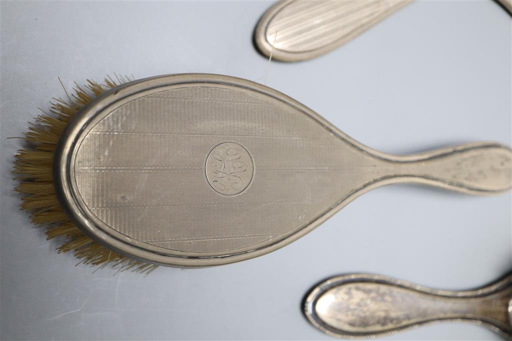 Two late 1920s silver mounted hand mirrors and three silver mounted brushes.